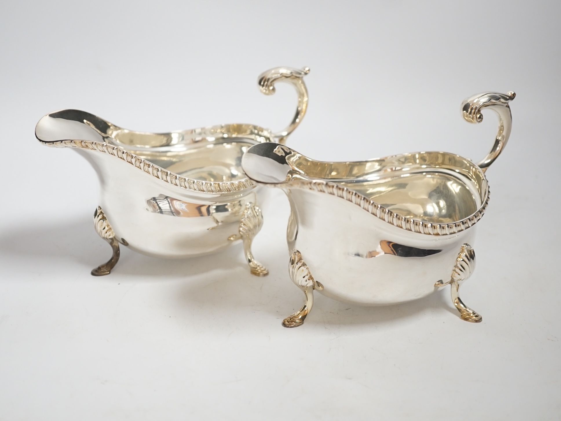 A pair of Elizabeth II silver sauceboats, with flying scroll handles, by Garrard & Co, London, 1961, length 17.9cm, 20oz.